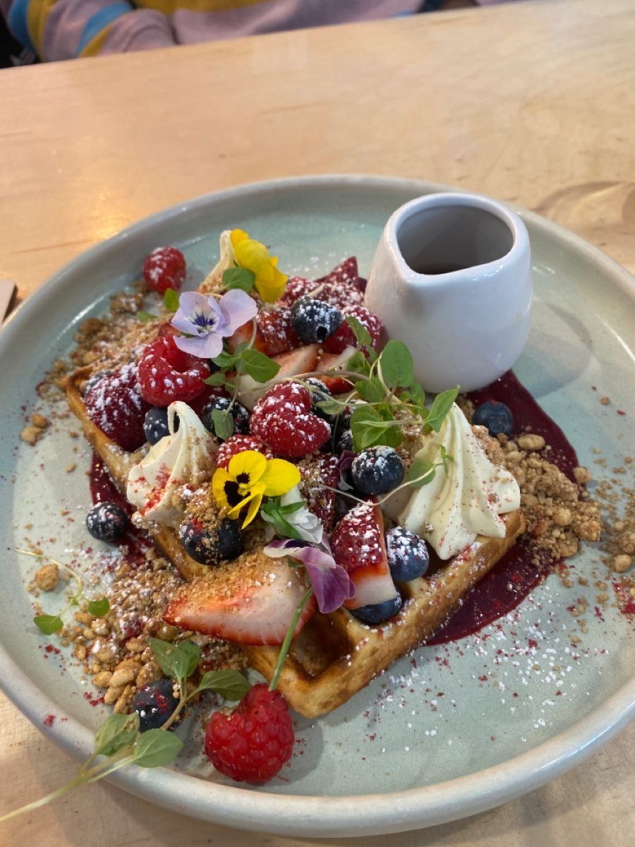 Waffle con frutti di bosco freschi, fiori eduli e sciroppo d'acero per il brunch in Isola Milano