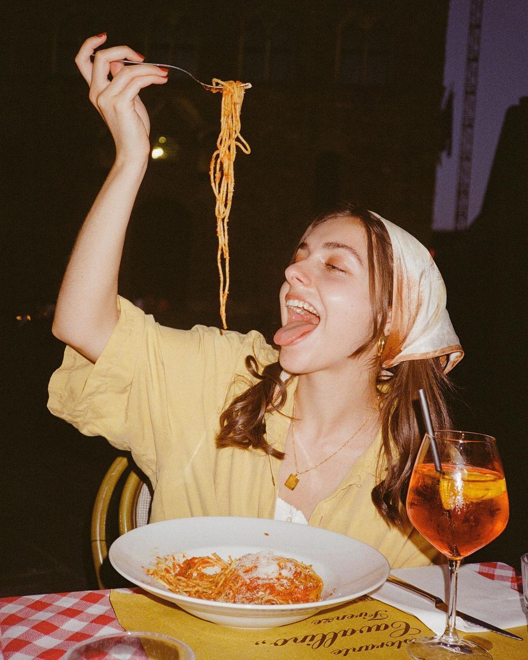 Ragazza che gusta spaghetti al pomodoro accompagnati da uno spritz durante la cena estiva da Vesper Milano